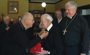 Fr Kevin O'Donoghue pins on Fr Bill's medal